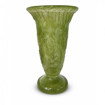 un vase vert posé sur une surface blanche