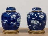 two blue vases with white flowers on them sitting on a table