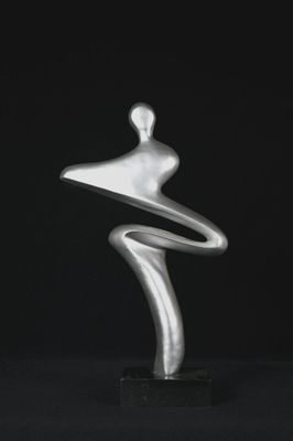 a silver sculpture of a woman standing on a black surface