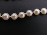 a close up of a necklace with pearls on a mannequin