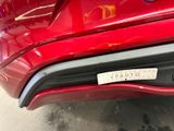 the rear end of a red car with a sticker on it ' s bumper