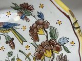 a yellow and blue plate with a bird and flowers on it