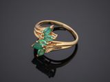 a gold ring with emerald stones on a black surface