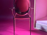 a red chair sitting in front of a mirror in a pink room