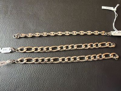 a pair of gold chain bracelets on a black surface
