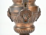 a bronze vase with a lion head on top of it