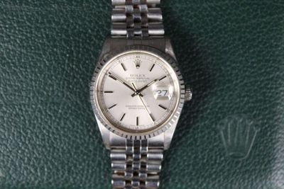 une photo d'une montre Rolex posée sur une surface en cuir vert