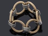 a close up of a silver and gold bracelet on a black surface