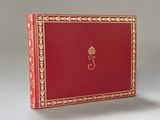 un vieux livre rouge aux tranches dorées, avec une couronne sur la couverture