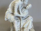 a white statue of a man and a woman sitting on a bench