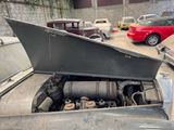 an old car with a broken hood sitting in a garage
