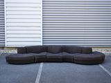 a large black couch sitting in a parking lot next to a building