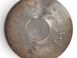 silver plate with birds and flowers on it on a white surface