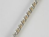 un gros plan sur une broche en forme de barre, en argent et en or