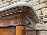 a wooden cabinet with a marble top in front of a brick wall
