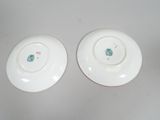 two white plates with green designs on them sitting on a table