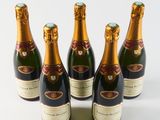 six bottles of champagne are lined up on a white surface
