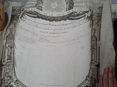 une personne tenant un livre sur lequel figure une illustration représentant des armoiries