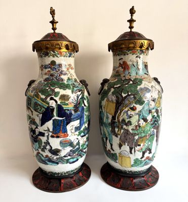 une paire de vases chinois ornés de scènes asiatiques, posés sur une surface blanche