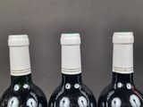three bottles of wine with eyes painted on them