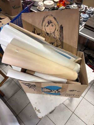 une boîte en carton remplie de papiers et d'autres objets, posée par terre