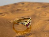 yellow gold ring with ruby and diamonds on a wooden surface