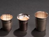 three shot glasses sitting next to each other on a black surface