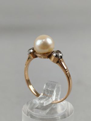 a close up of a ring with a pearl and diamonds on it