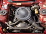 a red car with its hood open and the engine in the back
