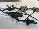 Plusieurs maquettes d'hélicoptères militaires sont exposées sur une surface blanche
