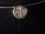 a close up of a silver necklace with a diamond on it