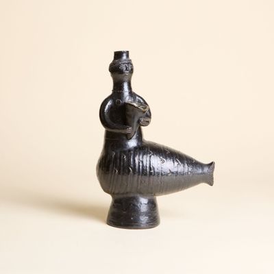 une image représentant un vase noir surmonté d'un oiseau
