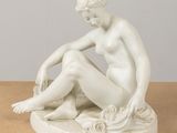 statue d'une femme assise sur un rocher, les jambes croisées