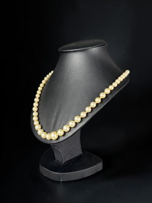 a close up of a necklace on a mannequin on a black background