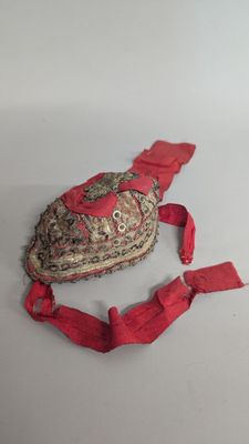 an old hat with a red ribbon around it on a white surface