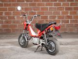 a small red motorcycle parked in front of a brick wall