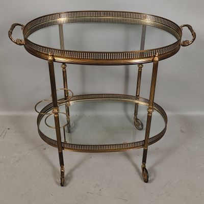 an image of a brass and glass bar cart on wheels