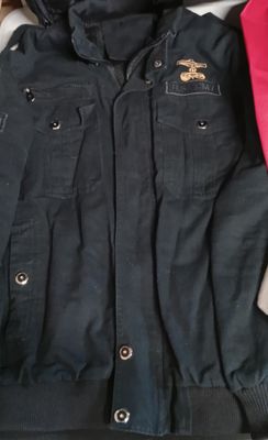 une veste noire et un chapeau rose posés sur un lit
