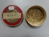 une petite boîte de paillettes dorées à côté d'une petite boîte de paillettes dorées