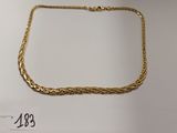 gros plan d'un collier en or sur une surface blanche