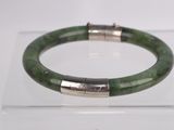 green jade bracelet with silver accents on display on clear acrylic display case