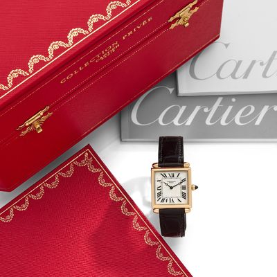 une boîte rouge sur laquelle est posée une montre, à côté d'une autre boîte rouge