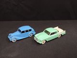 two toy cars sitting next to each other on a black surface