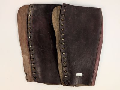 une paire de bottes en cuir marron ornées de clous, posées sur un fond blanc