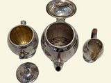a silver tea set with a cup and saucer on it