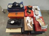 Plusieurs paires de chaussures sont empilées sur des cartons posés sur une table.