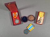 trois médailles et une médaille dans une boîte rouge