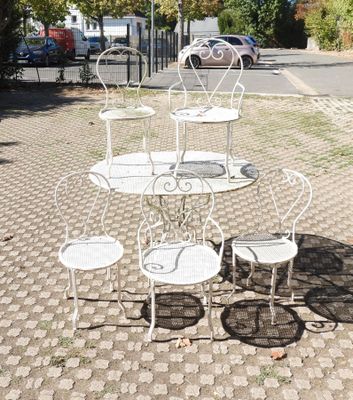 a white table and four chairs on a brick sidewalk