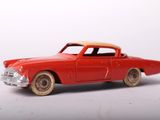 a red toy car that is sitting on a white surface