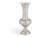 un vase en argent posé sur une surface blanche